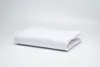 A white folded duvet cover is placed on a white surface with a light gray background. Produktbild-Vorschau