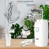 A collection of nebulizer components and the main device are displayed on a wooden surface with a blurred green plant in the background. Produktbild-Vorschau