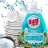 A bottle of Dual Power dish soap with a stack of clean dishes and a bowl of powder in the foreground, surrounded by water splashes and greenery. Produktbild-Vorschau