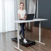 A woman is using a treadmill while working on a laptop at a standing desk in a modern room. Anteprima dell’immagine prodotto