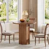 A dining set with a round table and chairs in a well-lit room with large windows. Produktbild-Vorschau