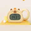A cute, cartoon-like alarm clock shaped like a capybara sits on a yellow platform. The clock displays the time and temperature. In the background, there are abstract yellow shapes. Náhled obrázku produktu