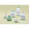 Several small trash bags with different colored ties are arranged on a light green background. Podgląd zdjęcia produktu