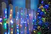 A string of colorful LED lights is wrapped around a wooden fence and a Christmas tree. Produktbild-Vorschau