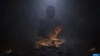 A large Buddha statue in a dark, atmospheric setting with small figures and candles. Náhľad obrázku produktu