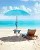 A beach scene with a lounge chair, umbrella, and side table. Produktbild-Vorschau