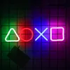 Four neon lights in the shape of PlayStation controller buttons (triangle, circle, cross, square) are displayed on a black grid background. Produktbild-Vorschau