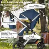 A blue stroller is shown outdoors in a park or garden setting, with a woman blurred in the background. The image highlights various features of the stroller with text overlays and arrows. Produktbild-Vorschau