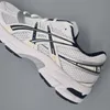 A close-up side view of a white and navy Asics athletic shoe against a plain gray background. Produktbild-Vorschau