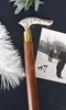 A close-up of a wooden cane with a decorative brass handle, placed next to a vintage photograph of people and a dog. Náhľad obrázku produktu