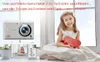 A young girl in a white dress sits on a windowsill holding a red heart-shaped box, with a digital camera and a smaller display of the camera in the foreground. Produktbild-Vorschau