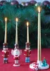 Christmas-themed candle holders with lit candles in front of a pine garland. Produktbild-Vorschau