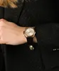 A close-up shot of a woman's wrist wearing a gold and silver watch with a black strap. Produktbild-Vorschau