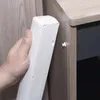 A hand is holding a white power strip near a wooden cabinet, demonstrating how it can be attached. Produktbild-Vorschau