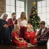 A family is gathered around a Christmas tree, opening presents. Produktbild-Vorschau