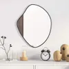 A mirror with a wooden accent is displayed on a white wall above a white dresser. Decorative items like a branch in a vase, a candle in a lantern, an alarm clock, and wooden bird figures are arranged on the dresser. Produktbild-Vorschau