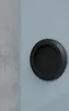 A close-up shot of a black sliding door handle on a light blue door, with a textured gray wall on the left. Produktbild-Vorschau