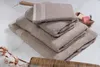 A stack of folded towels on a marble surface, with cotton sprigs and a comb in the foreground, and soaps in the background. Produktbild-Vorschau