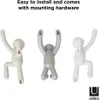 Three wall hooks shaped like stylized human figures are displayed against a white background. Náhled obrázku produktu
