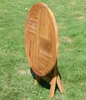 A round wooden garden table is shown folded and standing upright on a grassy lawn. Produktbild-Vorschau
