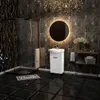 A modern, luxurious bathroom with dark marble tiles, a white vanity with a sink, a round illuminated mirror, and a glass shower enclosure. Náhľad obrázku produktu