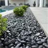 Schwarze Kieselsteine als Beetabdeckung entlang einer modernen Terrasse im Garten Produktbild-Vorschau