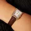 A close-up shot of a woman's wrist wearing a rectangular analog watch with a brown leather strap. Anteprima dell’immagine prodotto