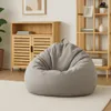 A light gray bean bag chair sits on a cream rug in a room with wooden furniture. Produktbild-Vorschau
