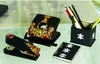 A collection of decorated black office supplies, including a stapler, hole punch, pencil holder, and notebook, arranged on a table. Anteprima dell’immagine prodotto