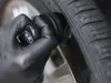 A gloved hand is using a brush to clean a tire. Anteprima dell’immagine prodotto