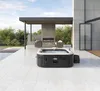 An Intex Pure Spa Greystone Deluxe hot tub is set up on a modern patio with a fireplace and seating area in the background. Náhľad obrázku produktu