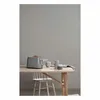 A modern gray toaster with a piece of toast in it sits on a wooden table next to two mugs. A white wooden chair is positioned at the table. Náhled obrázku produktu