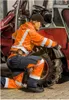 A person in workwear is kneeling next to the tire of a red vehicle. Produktbild-Vorschau