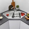 A corner kitchen sink with a faucet, tomatoes, and a plant. Podgląd zdjęcia produktu