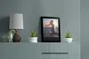 A framed picture and decorative items are displayed on a shelf above a cabinet. Produktbild-Vorschau