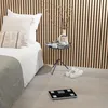 A bedroom scene with a bed, a side table, and a digital scale on the floor. Produktbild-Vorschau