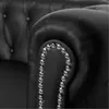A close-up view of the armrest of a black leather Chesterfield sofa, showing the tufted detail and decorative studs. Produktbild-Vorschau
