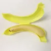 A yellow banana-shaped case is open, with a banana inside the bottom half. Produktbild-Vorschau