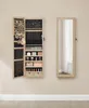 A jewelry cabinet with its door open, displaying various jewelry and makeup items, stands next to a full-length mirror on a wall. Produktbild-Vorschau
