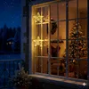 Christmas decorations in a window at night with snow falling. Voir les images du produit
