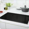 A modern kitchen countertop with a black glass ceramic hob, a pot with a lid, stacked plates, a potted herb, and bottles of oil and vinegar. Náhľad obrázku produktu