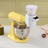 A yellow KitchenAid stand mixer with a white flour dispenser attachment. Produktbild-Vorschau