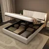 A white storage bed with its mattress lifted to reveal storage compartments filled with items. Náhľad obrázku produktu