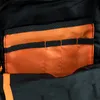 A close-up view of the interior of a black backpack, showing an orange fabric lining with multiple pockets. Produktbild-Vorschau