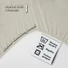 A close-up of a beige fabric with text overlays and care instructions. Produktbild-Vorschau