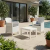 A white wicker patio set with two chairs and a table is placed on a tiled patio next to a swimming pool. Produktbild-Vorschau