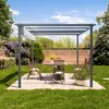 A pergola with a table and chairs set up in a backyard garden. Voir les images du produit