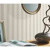 A close-up of a wall with striped wallpaper, a framed picture, an open book, and a decorative vase with a sculpture. Náhľad obrázku produktu
