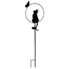 A black silhouette of a cat sitting inside a circular frame with a butterfly above it, mounted on a stake with a solar panel at the base. Produktbild-Vorschau