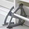 Close-up view of the internal mechanism of a white shoe cabinet, showing gray metal brackets and white wooden shelves. Produktbild-Vorschau